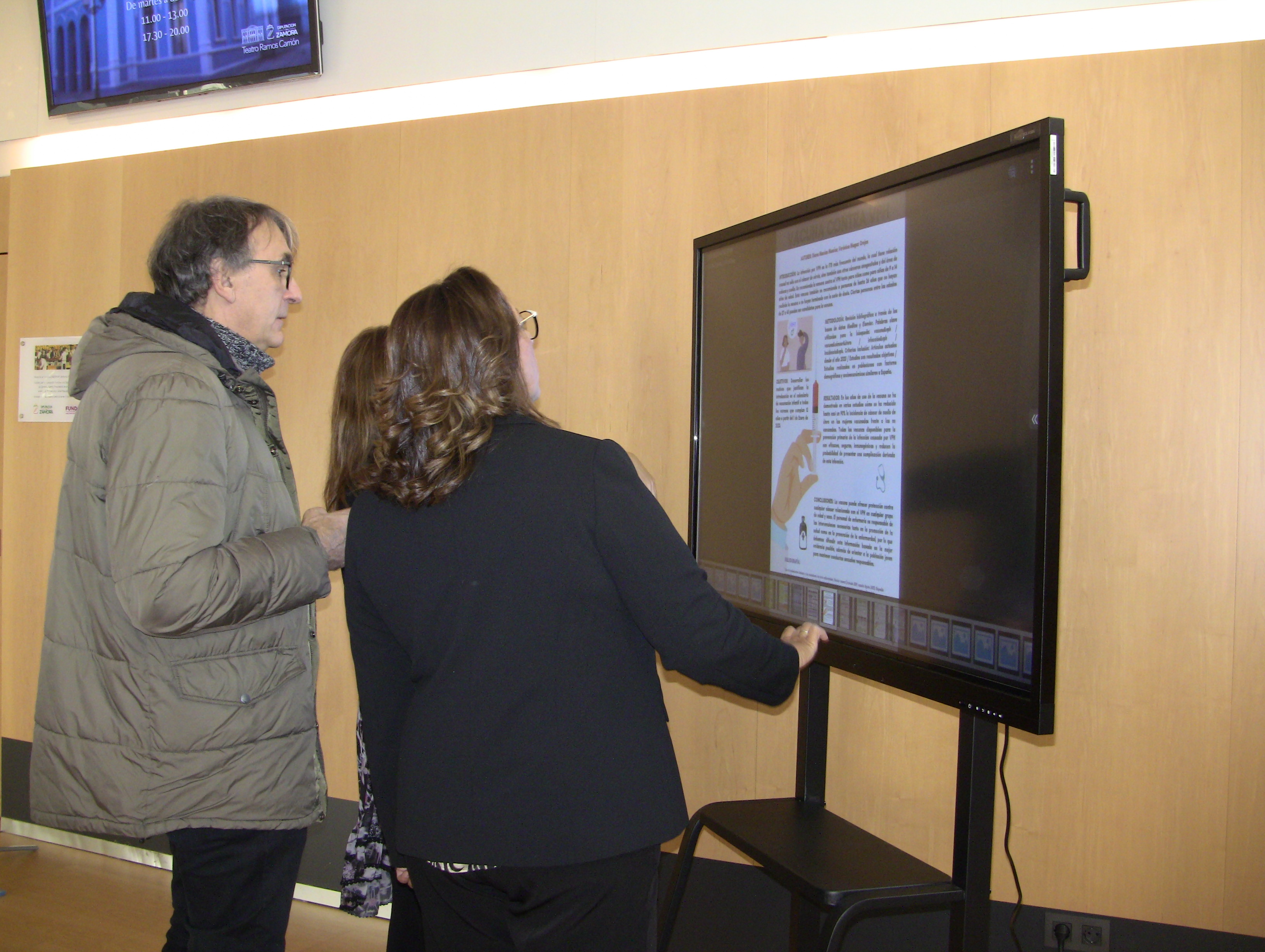 La secretaria general de SATSE Castilla y León, Mercedes Gago, observa los pósteres presentados junto a otros asistentes